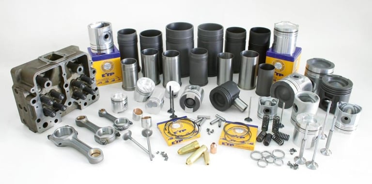 Assorted engine parts and components including cylinder head, pistons, rings, gaskets, and various metal components displayed on white background